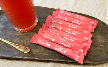 7 pink grapefruit drink mix sachets next to a glass of drink