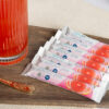 7 pink grapefruit drink mix sachets next to a glass of drink