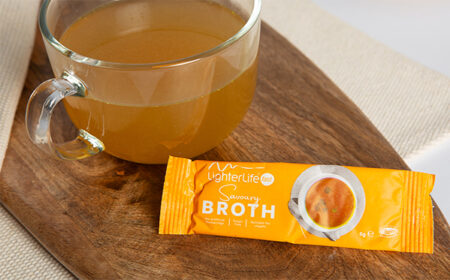 savoury broth in a glass mug next to sachet
