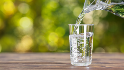 A jug pouring water into a glass on a table.